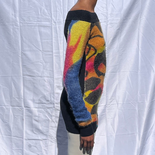 Person wearing a colorful standing infront of a white fabric surface