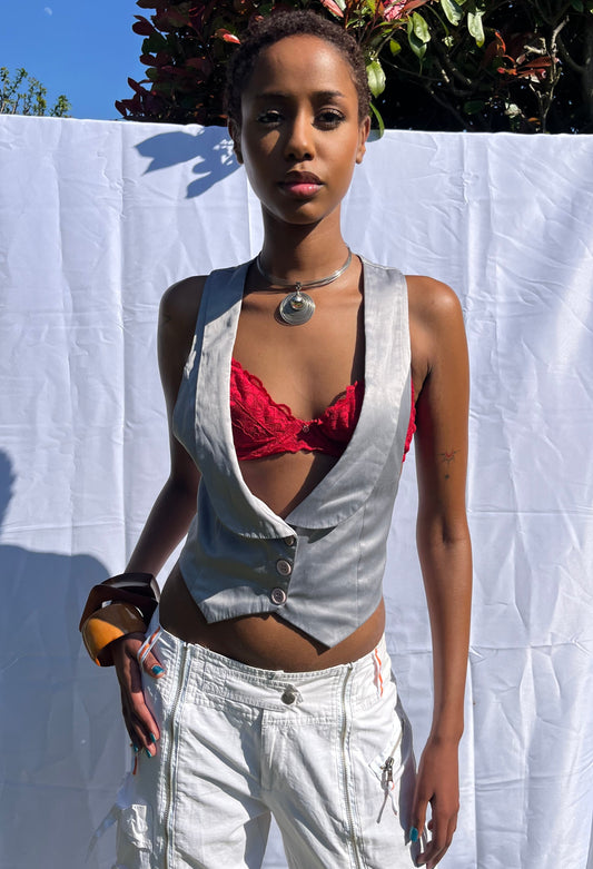 Person wearing a metallic top and white pants on a white sheet outdoors